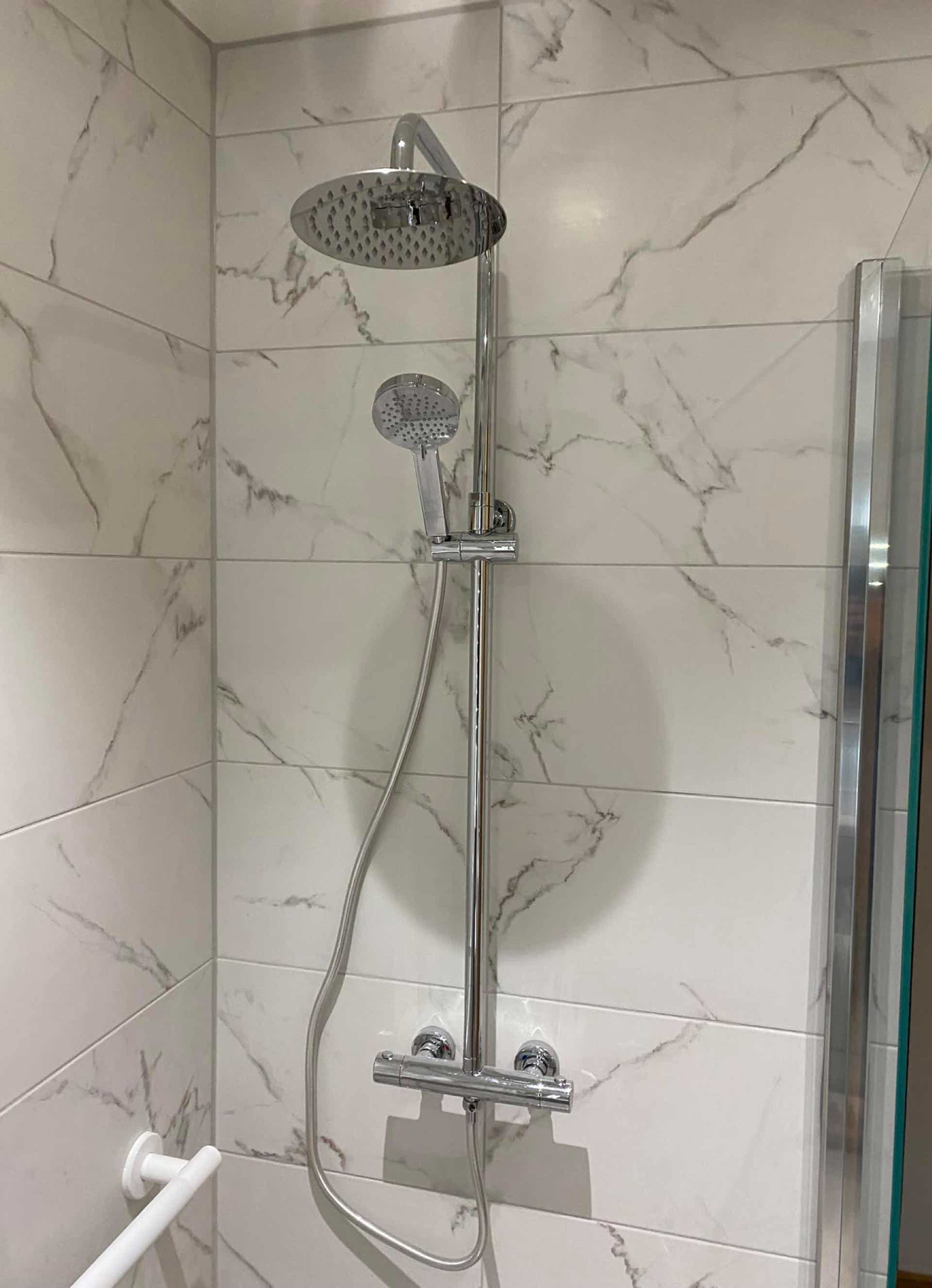 Shower fitting in white tiled bathroom and accessiblity fixtures installed by Plumb Yorkshire Ltd.