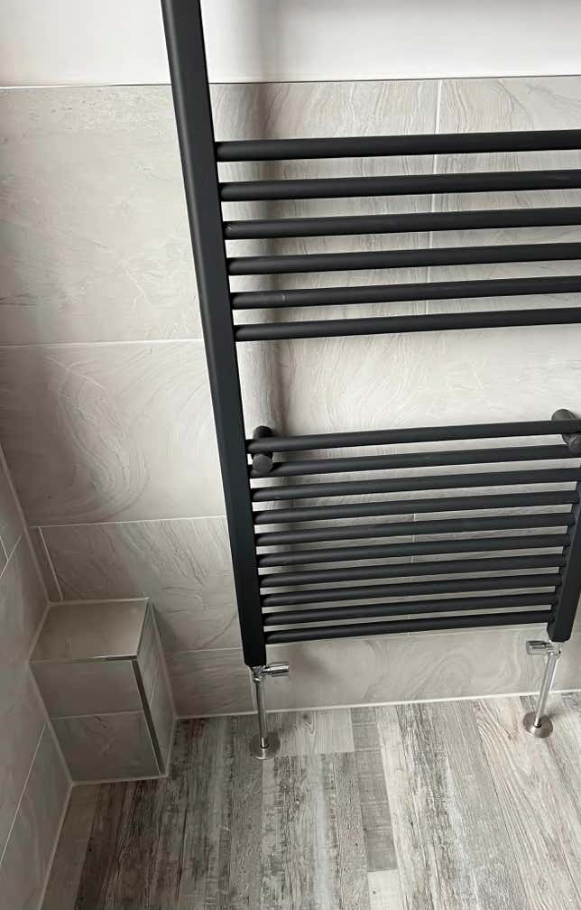 Modern matt-black vertical radiator fitted by Plumb Yorkshire Ltd. bathroom fitters.