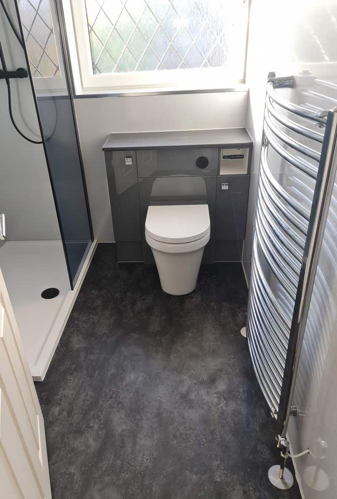 Modern white toilet pan with hidden cistern in grey housing in a compact but fully formed shower room installed by Plumb Yorkshire Ltd.
